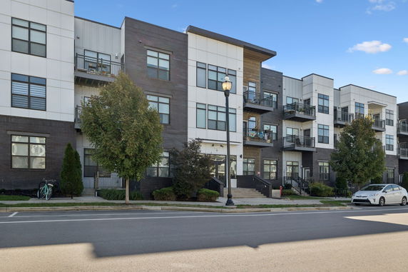 Front view of a modern multi-story apartment building with balconies.
