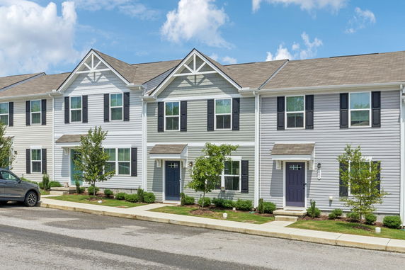 Front view of a row of townhouses with gabled roofs and multiple windows.
