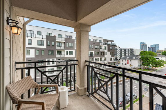View from a balcony overlooking adjacent buildings and street below.