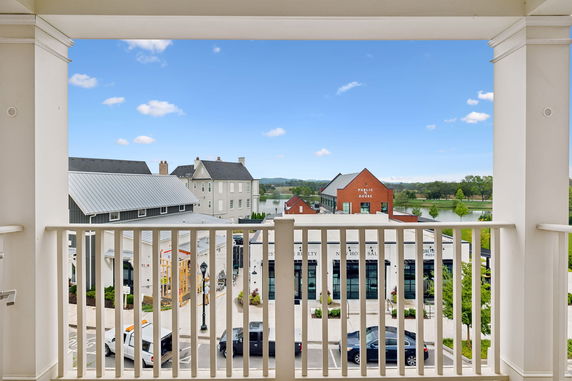 View from a building balcony showing a town area with multiple buildings and a distant lake.