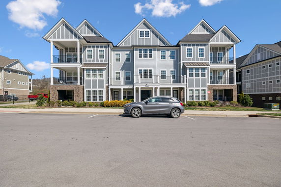 Front view of a multi-story residential building with balconies and gabled roofs.
