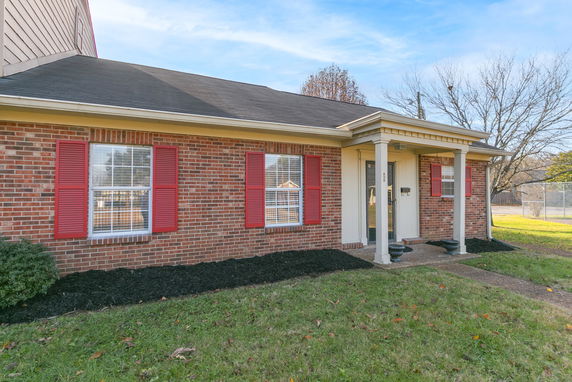 Front view of a single-story brick house with red shutters and a small porch.