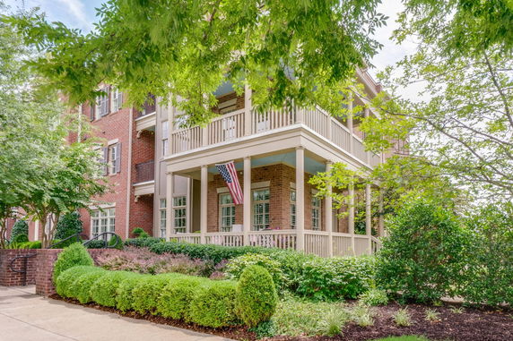 Front view of a brick house with balconies and an American flag.