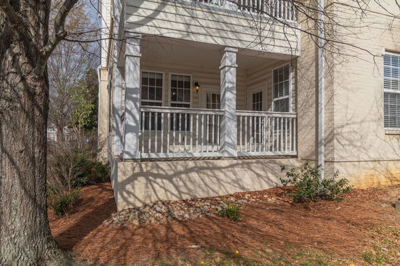 Front view of a house with a small covered porch and white railing.