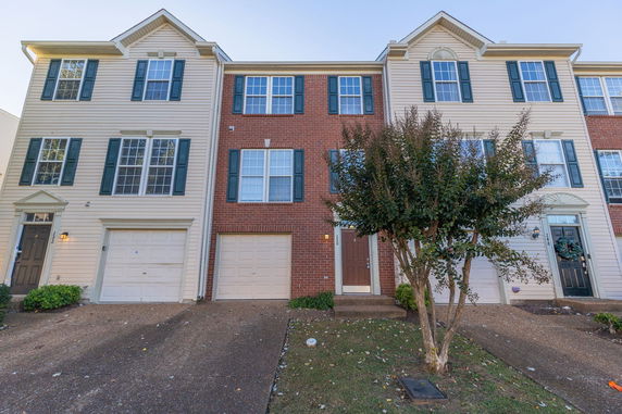 Front view of a three-story townhome with brick and siding facade.