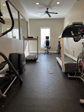 Indoor gym area with exercise equipment including treadmills and other fitness machines.