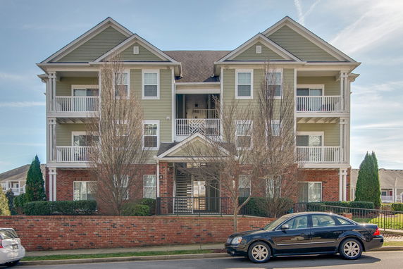 Front view of a multi-story residential building with balconies and a brick facade.