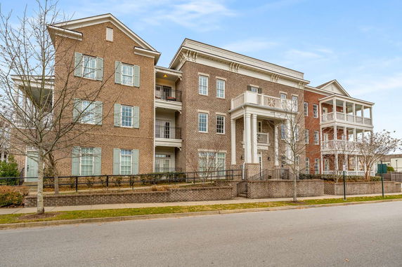 Front view of a multi-story brick building with balconies and white trim.