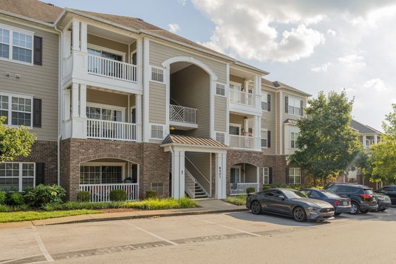 Front view of a multi-story residential building with balconies and parking area.