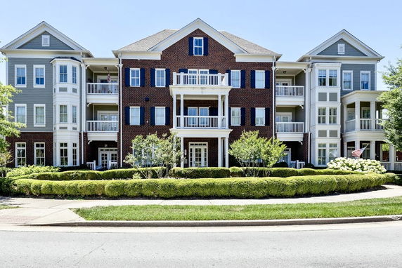 Front view of a multi-story residential building with multiple balconies and a mix of brick and siding exterior.