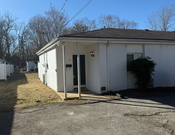Front view of a single-story house with white brick exterior and a small porch.