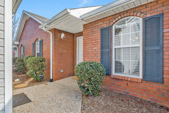 Front view of a brick single-story house with arched windows and blue shutters.