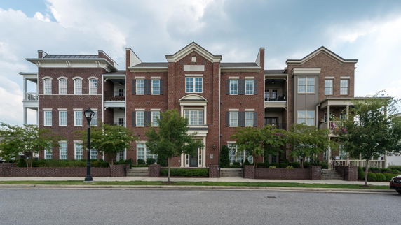 Front view of a multi-story brick building with balconies and shutters.