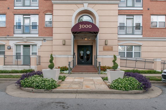 Front view of a multi-story building with an entrance featuring an awning and decorative planters.