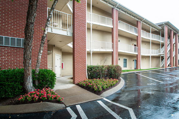 Front view of a multi-story building with brick columns and balconies.