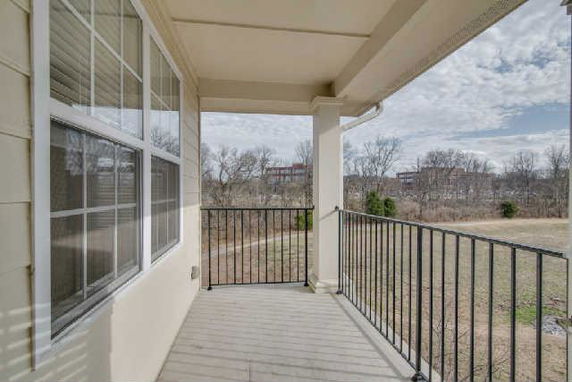 Balcony area of a building overlooking open land with trees and distant buildings.