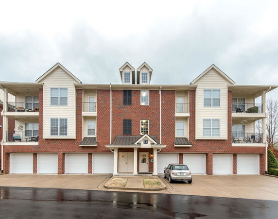 Front view of a multi-story apartment building with garages on the ground level.