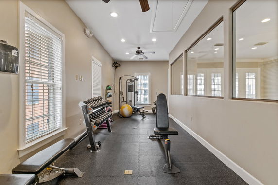 Interior view of a small gym with exercise equipment and weights.