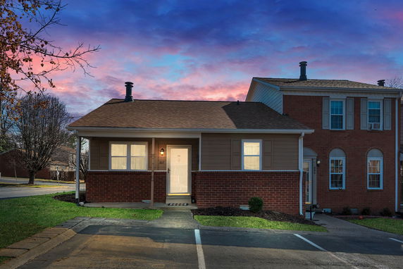 Front view of a single-story house with a brick exterior and porch lighting.