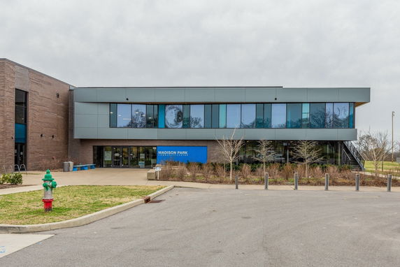 Front view of a modern, two-story building with large glass windows and a brick facade.