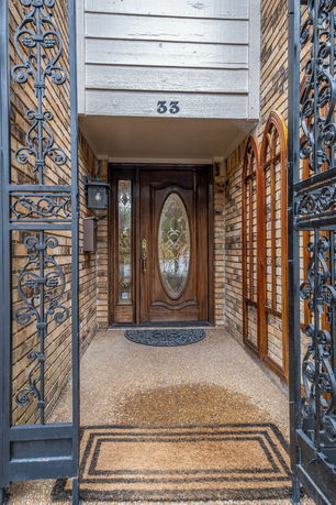 Front entrance of a house with a wooden door and decorative iron gate.