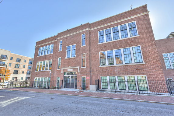 Front view of a three-story brick building with large windows.