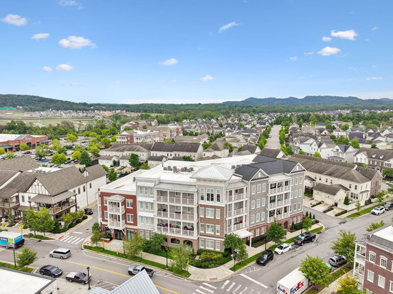 Panoramic view of a neighborhood with apartment buildings, houses, and distant hills.