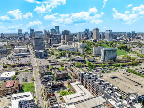 Aerial view of a cityscape with numerous buildings and skyscrapers under a blue sky with clouds.