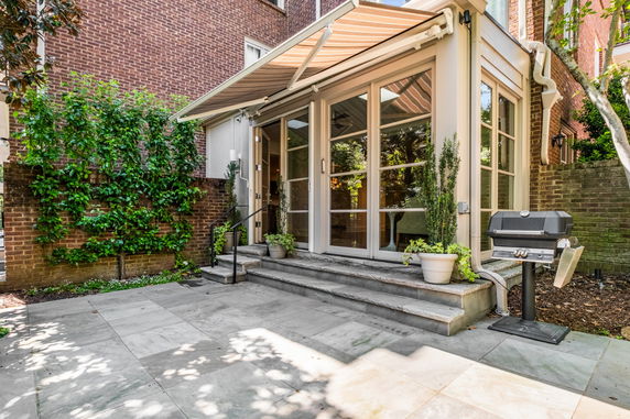View of a house with a patio, glass doors, and an awning.