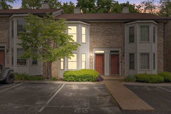 Front view of a multi-story townhouse with brick and siding exterior, double entry doors, and parking area.