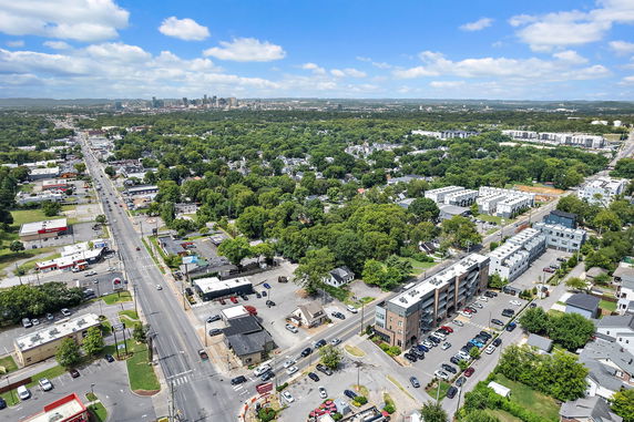 Panoramic view of a cityscape with roads, buildings, and greenery under a blue sky.