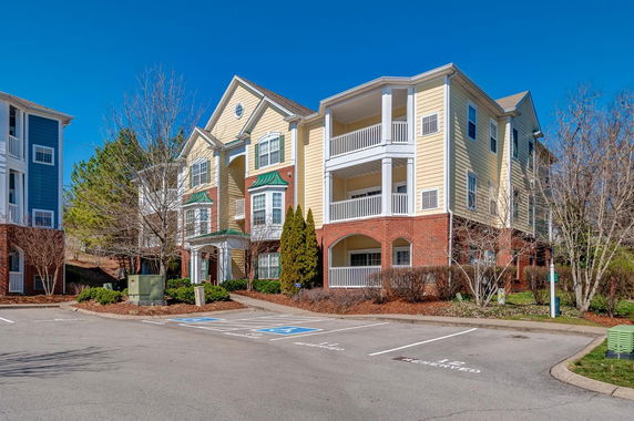 Front view of a three-story apartment building with balconies and a brick facade.