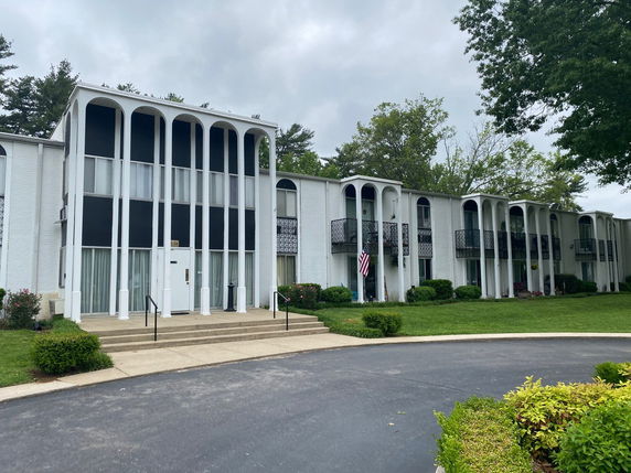 Front view of a two-story building with white pillars and balconies.