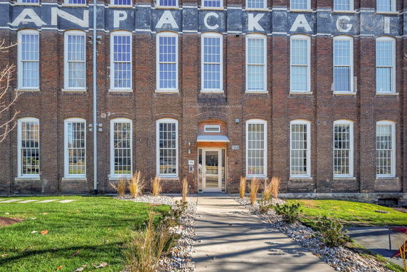Front view of a large brick building with multiple tall windows and an entrance.