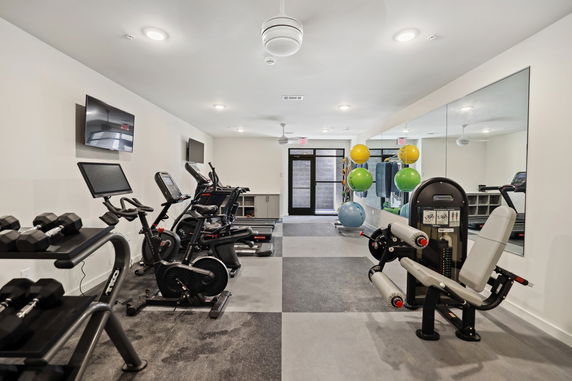 Interior view of a modern gym with exercise equipment and mirrors.