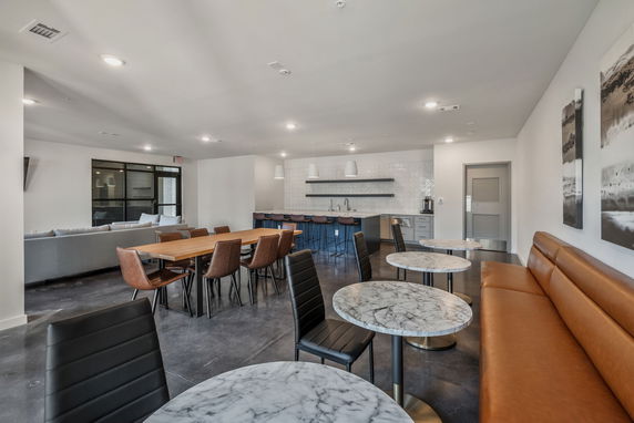 Interior view of a clubhouse with tables, chairs, and a bar area.