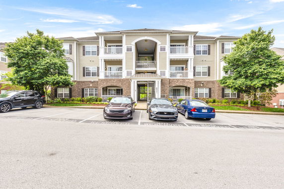 Front view of a three-story building with balconies and parking area.