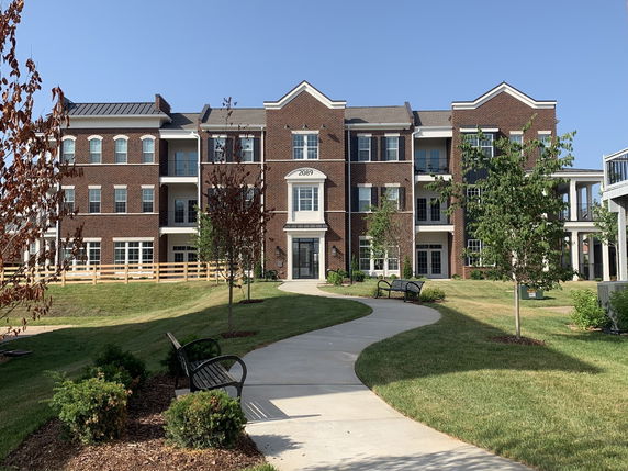 Front view of a multi-story brick building with a central entrance and balconies.