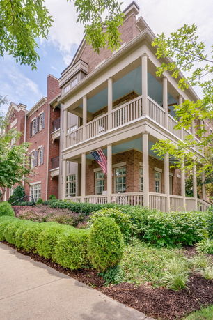 Front view of a multi-story brick building with balconies and an American flag.