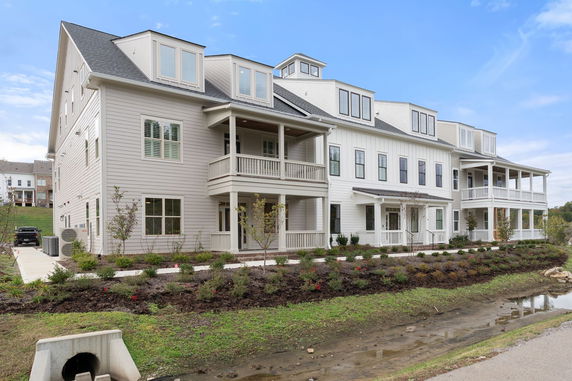 Front view of a multi-story residential building with balconies and a sloped roof.