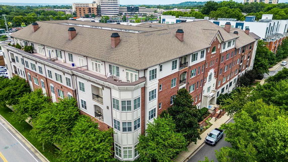 Front view of a large multi-story brick residential building with pitched roofs and balconies.