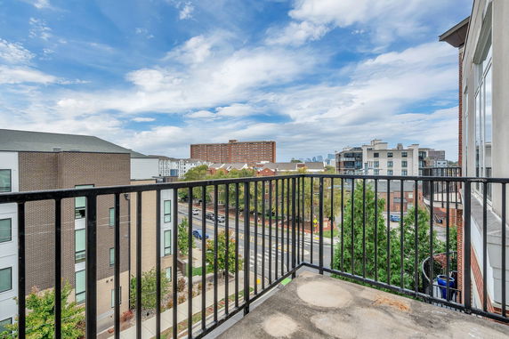 View from a balcony showing surrounding urban area with buildings and trees.
