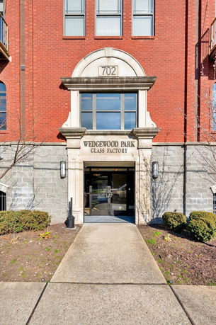 Front view of a brick building entrance with large windows and an arched doorway.