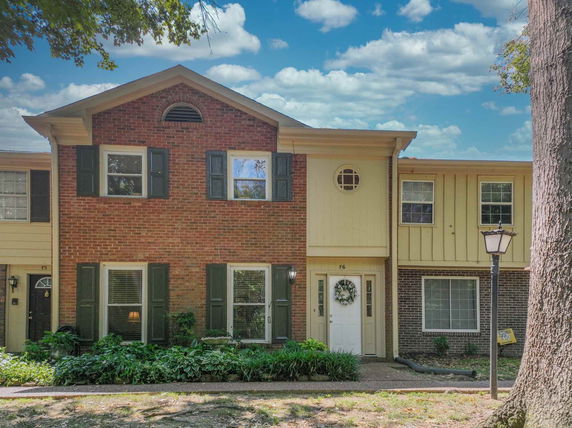 Front view of a two-story townhouse with brick and siding exterior.