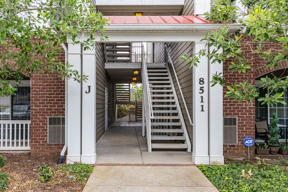 Front view of a building entrance with red roof and staircase.