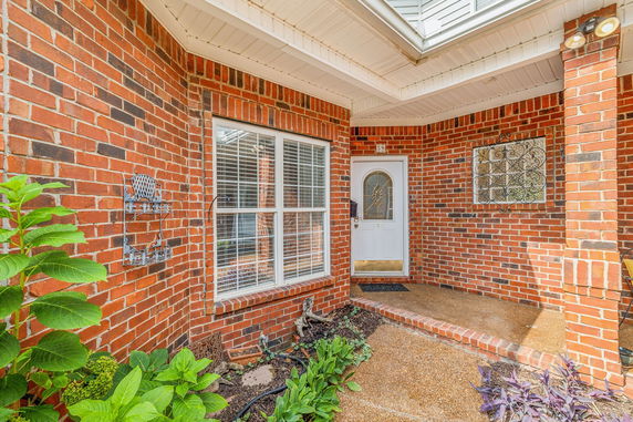 Front view of a brick house entrance with a white door and a window.