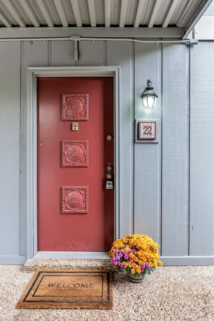 Front view of a house entrance with a red door and flower pot.