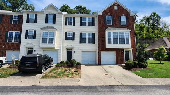 Front view of a multi-story townhouse with garages and a driveway.