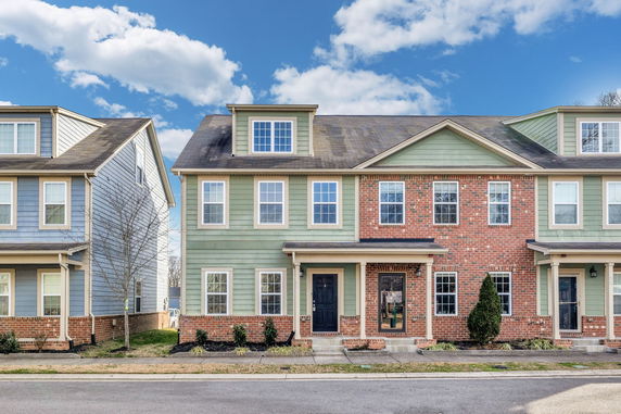 Front view of a two-story townhouse with brick and siding facade.