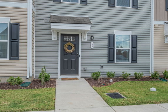 Front view of a house with a dark door, white trim, and blue-gray siding.